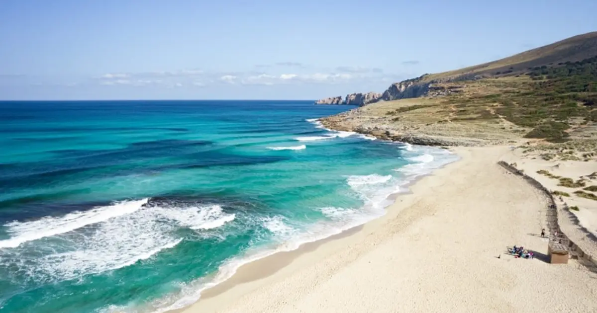 Orilla de arena fina y oleaje turquesa en la amplia playa natural de Cala Mesquida