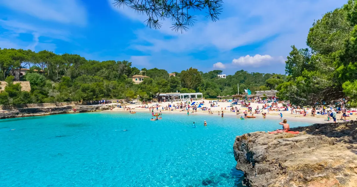 Bañistas disfrutando del agua turquesa en la playa de arena de Cala Mondragó