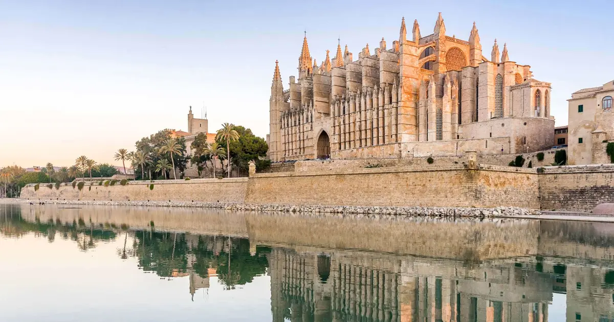 Fachada gotica de la Catedral de Palma y sus murallas reflejadas en las aguas del Parc de la Mar