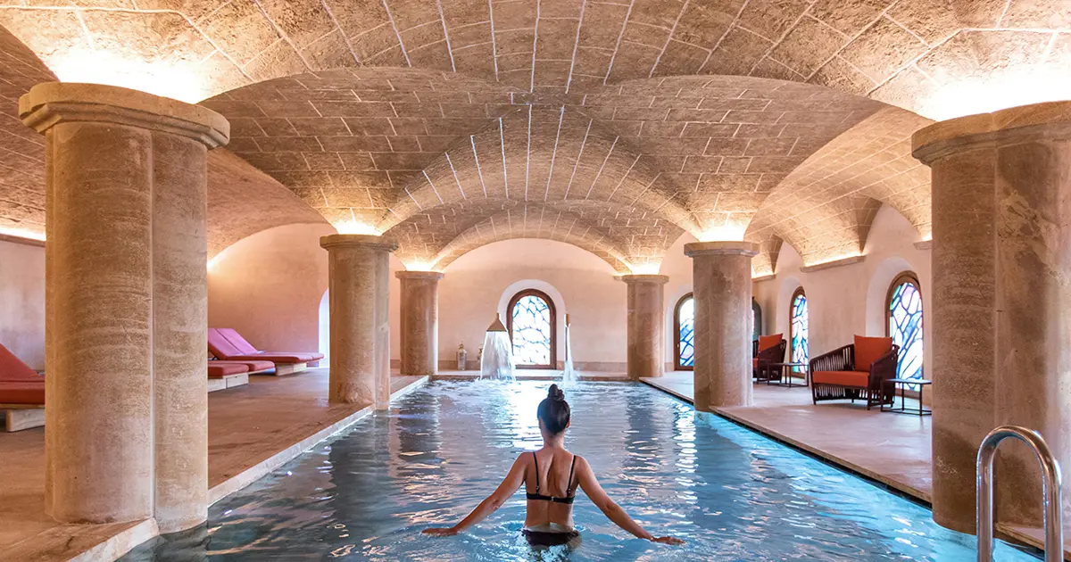 Piscina climatizada bajo arcos de piedra en el spa del Hotel Creu de Tau en Capdepera