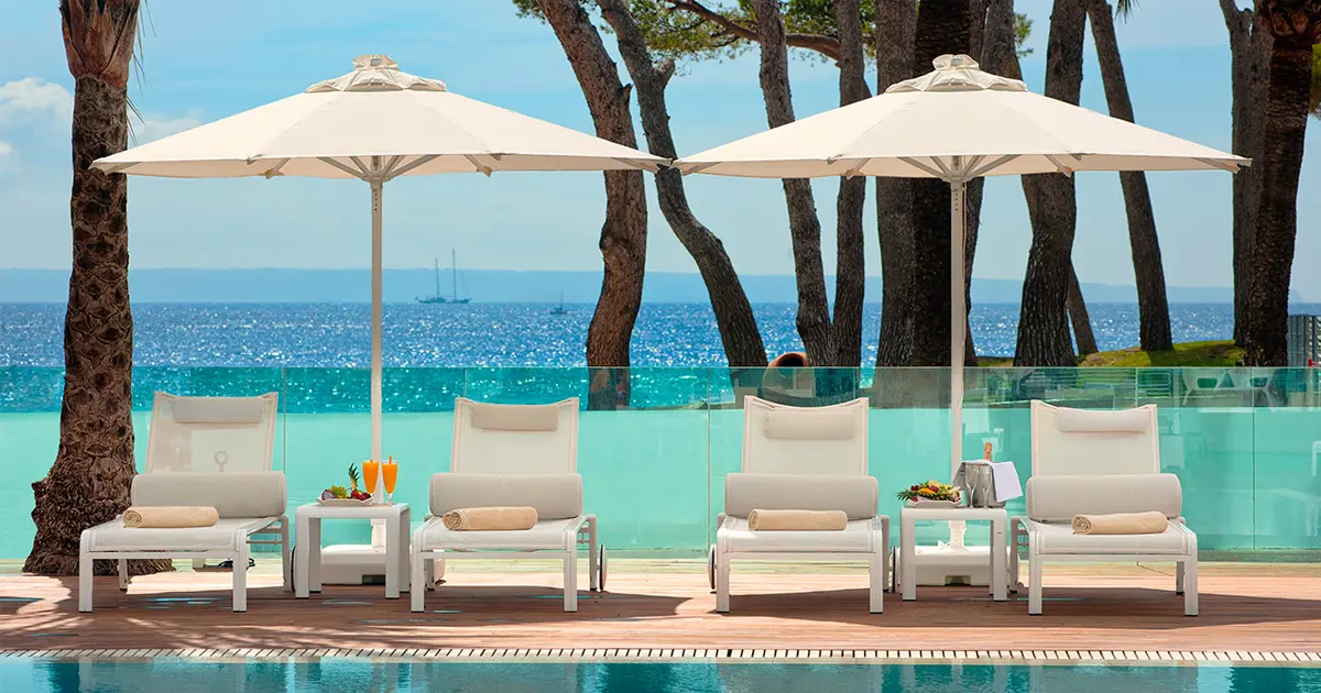 Zona de piscina y solárium con hamacas y vistas al mar en un hotel de Mallorca