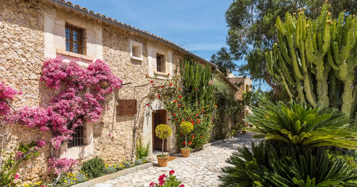 Entrada de piedra cubierta de buganvillas en el Petit Hotel Son Ametler Mancor de la Vall