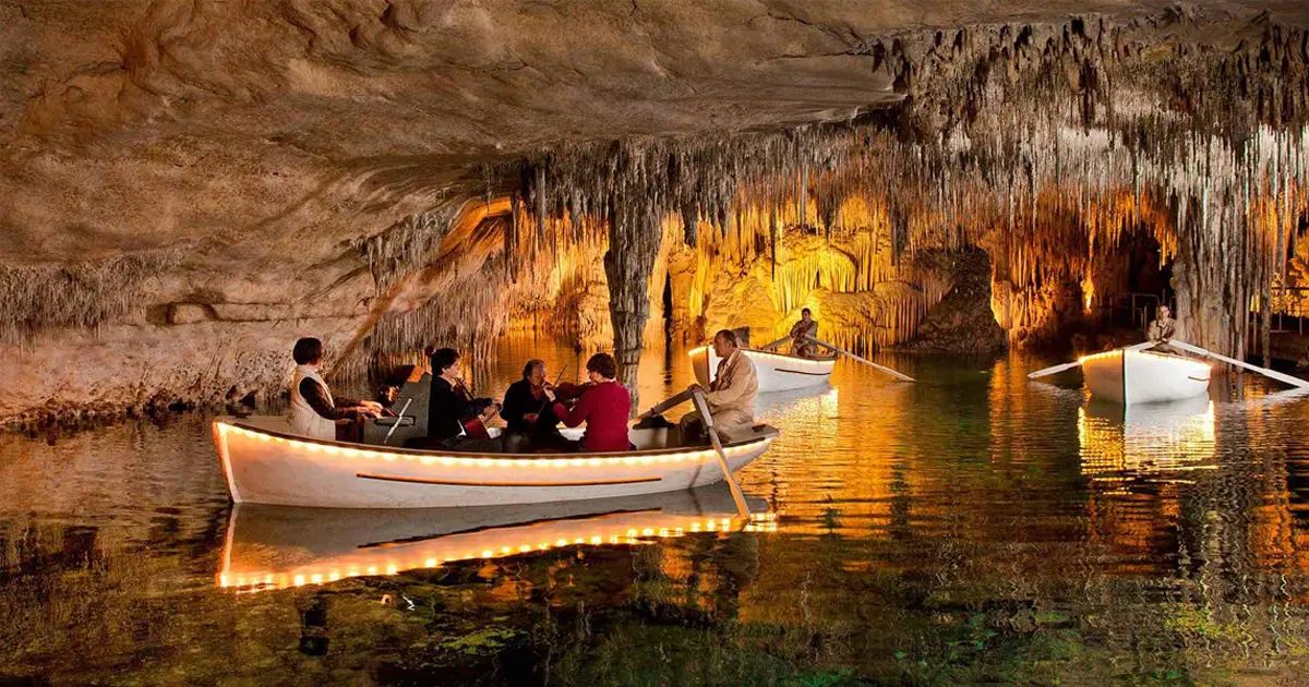 Barca iluminada navegando por el lago subterraneo de las Coves del Drach