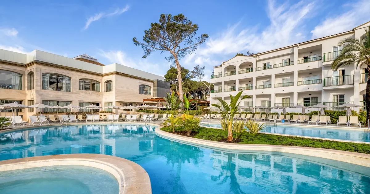 Piscina exterior curvada y edificio del resort Viva Cala Mesquida en Capdepera